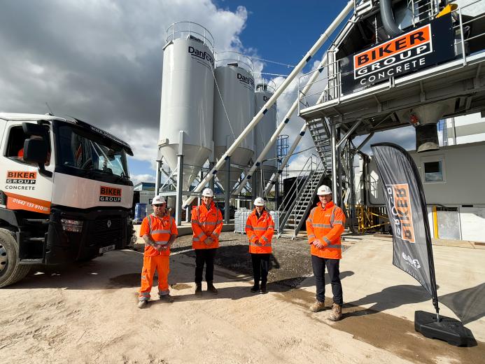 Four people in orange PPE stand in front of Biker Group’s new Stockton-on-Tees concrete plant, which represents a £1.5 million investment in the region.
