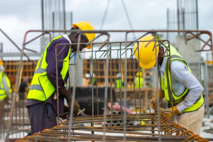 Two men in PPE working on rebar on a construction site