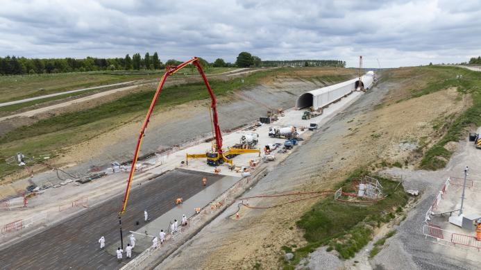 A red concrete boom placing concrete for the base of what will become the north portal of Chipping Warden green tunnel May 2025