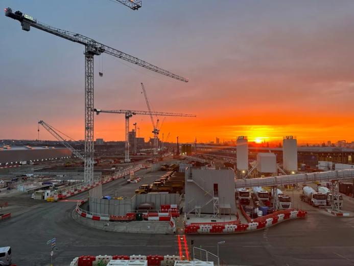 Sunrise over the construction of Old Oak Common Station in London, one of several HS2 sites supplied by Holcim UK, with a tower silhouetted against a setting sun