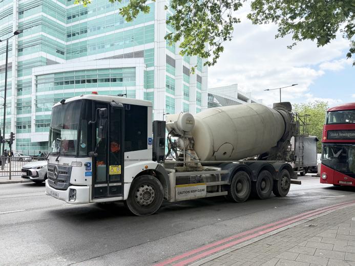 A concrete mixer drives along a street in London with a red double decker following 
