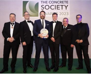 A group of men in dinner suits collect an award