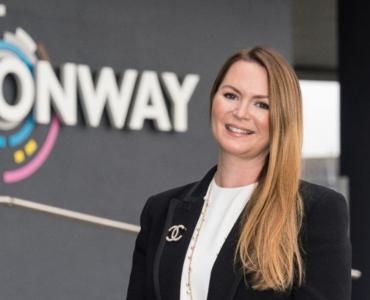 A woman standing in front of FM Conway's logo