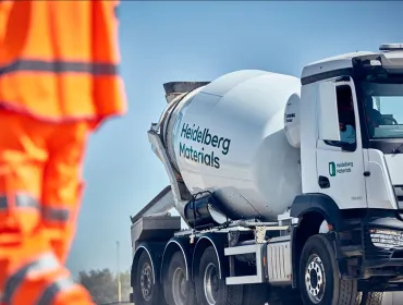 A man in orange PPE and a Heidelberg Materials concrete truck mixer