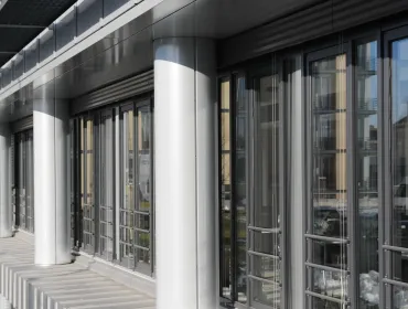 A glass fronted office with concrete columns.