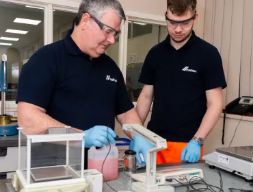 Two men in black and safety goggles working on Cemex’s Prime admixtures in its lab 