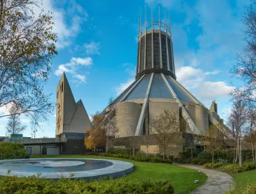 A view of Liverpool Metropolitan Cathedral in early summer with trees and a pond