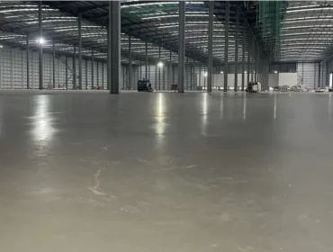 A large, newly poured concrete floor inside a large warehouse