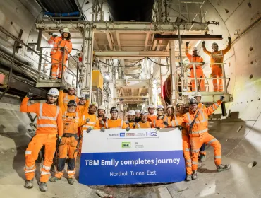 A large group of people in orange PPE, part of HS2 tunnelling team celebrates, TBM Emily completing 5.5km journey. Image: HS2.