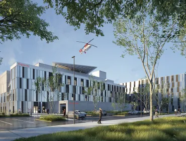 A red helicopter flies over the new Caen University Hospital, which features 110,000 m² of healthcare space built using lower-carbon concrete. Photo Credit: ©CHU de Caen Normandie