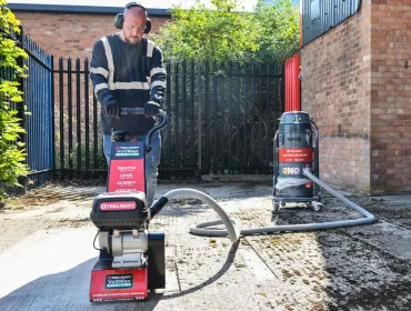 A man with beard using one of Trelawny’s new VoltMax range, which includes a grinder, scarifier and stripper – all powered by 82V lithium-ion batteries, prepares a surface for construction work