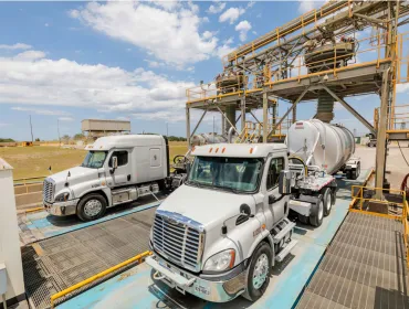 Two US trucks load up with materials at Eco Material Technologies, which supplies supplementary cementitious materials, critical for reducing embodied carbon in concrete.