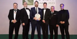 A group of men in dinner suits collect an award