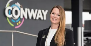A woman standing in front of FM Conway's logo