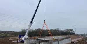 A crane lifting concrete beams to construct a road bridge