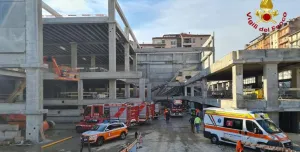 A picture of a building that was under construction but has collapsed with emergency vehicles