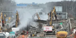 A motorway bridge being demolished using several large excavators
