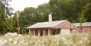 A small single storey house on the edge of a wood