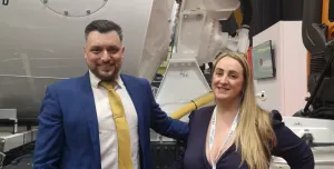 A man and a woman stading in front of a concrete mixer