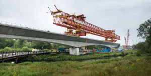 A picture of an orange launching girder sitting on top of an under construction railway viaduct