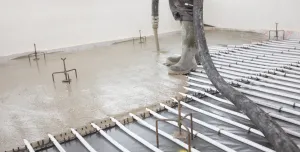 A picture of a man's legs and a concrete floor being screeded