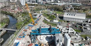 An aerial shot of a construction site with a yellow crawler crane and a large blue gantry crane