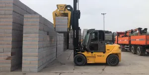 A yellow forlift stacking concrete plinths