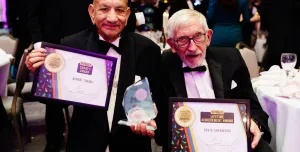 Two old men in DJs holding award certificates