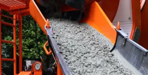 A close up of an orange cement mixer's chute discharging concrete