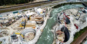 A large construction site divided by a bend in a river