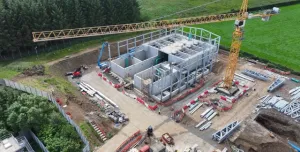 Aerial view of an under construction waste water treatment works with a yellow tower crane