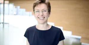 A head and shoulders photo of a woman with short hair, glasses and wearing a black tshirt