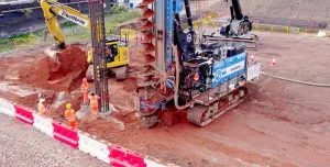 A blue piling rig and a yellow excavator at work on a construction site