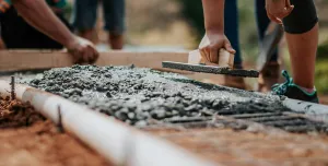 Men spreading wet concrete in a mesh mould