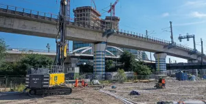 A yellow piling rig stands in front of a bridge on a construction site in Germany