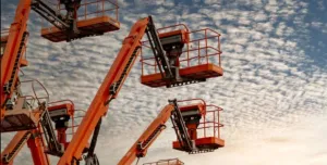 Orange aerial work platforms set against a backdrop of white, fluffy clouds