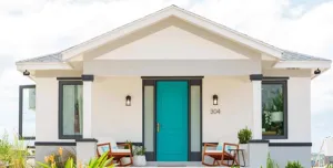 A white, single storey house with a green door