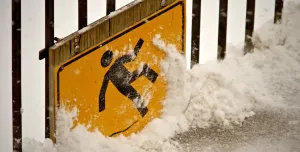 A health and safety sign of a person slipping on ice, covered in snow