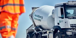 A man in orange PPE and a Heidelberg Materials concrete truck mixer
