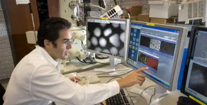 A man in lab clothes looking at monitors in a laboratory
