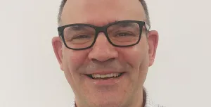 Head and shoulders picture of a smiling man in glasses