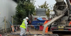 Workers at a construction site spread concrete being discharged by a mobile concrete mixer