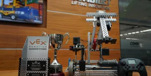 The Vex Robotics Awards on a table in front of a Combilift sign and video display showing a yellow and blue robotic vehicle