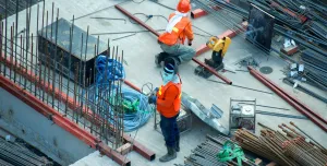 Two PPE clad construction workers install rebar ties