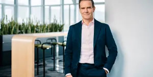 Dr Dominik von Achten, in dark suit and open neck shirt, standing in an empty office, has been elected the new president of GCCA, is chairman of the managing board at Heidelberg Materials