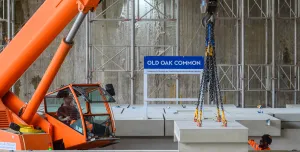 An orange crane and orange PPE-clad worker installing the first platforms at HS2's Old Oak Common station for HS2 trains.