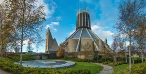 A view of Liverpool Metropolitan Cathedral in early summer with trees and a pond