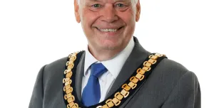 A photo of Paul Gandy, president, CIOB, wearing a grey suit, white shirt, blue tie and ceremonial chain.