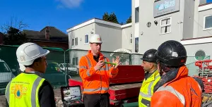 Men in a variety of PPE in front of a dental surgery discuss PERI UK and SWS's integrated waterproofing and formwork solution