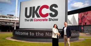 Richard Bradbury (right), Managing Director of The QMJ Group with Helaena Ackers, Exhibition Sales Account Manager, The NEC shake hands outside the NEC in front of a huge UK Concrete Show sign, following the signing of a two-year deal that sees the flagship trade show to stay at Birmingham’s NEC through 2027, with free parking and expanded plans for 2026 edition